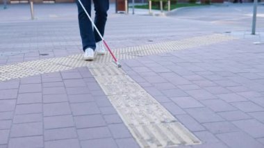 Kör insan bacakları baston kullanarak özel dokunsal fayansları arıyor. Sokakta bastonla yürüyen kör bir adam.