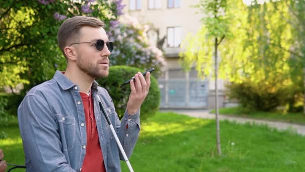 Blinde man met een handicap met behulp van digitale assistent en gemakkelijke toegang functies op de smartphone — Stockvideo