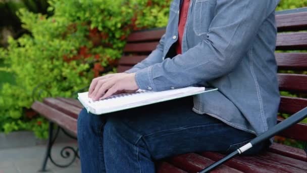 Hombre ciego leyendo el libro Braille, sentado en el banco en el parque de verano — Vídeo de stock