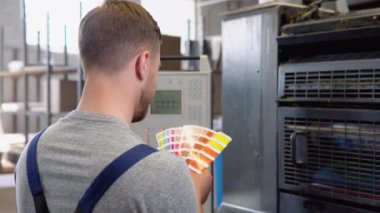 Grafik tasarımcısı renk paletinden renkler seçiyor. Baskı üretim sürecinde renk yönetimi kavramı. Yazdırma düzeltmesi için katalog örnekleri