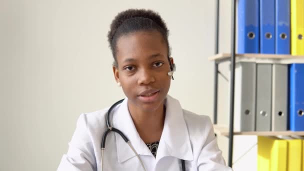 Jeune afro-américaine médecin ayant chat ou consultation sur un ordinateur portable regardant directement à la caméra — Video