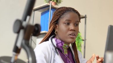 Genç Afro-Amerikalı kadın tıbbi danışman video dersi veriyor. Doktor kulaklık takıyor ve internette tıbbi bir konferans düzenliyor.