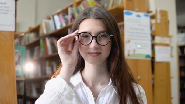 Una Ragazza Sorridente Con Gli Occhiali Legge Libro Nella Biblioteca — Video Stock