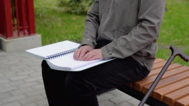 Şehir parkında bankta oturan kör bir adam kabartma kitap okuyor.