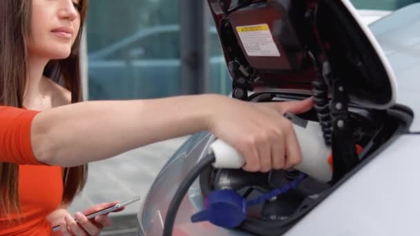 Een Vrouw Stopt Een Oplader Haar Elektrische Auto Gebruikt Telefoon — Stockvideo