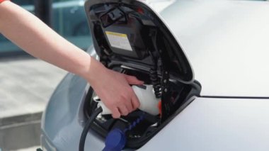 Elektrikli arabasının şarj aletini çıkaran bir kızın el görüntüsü.
