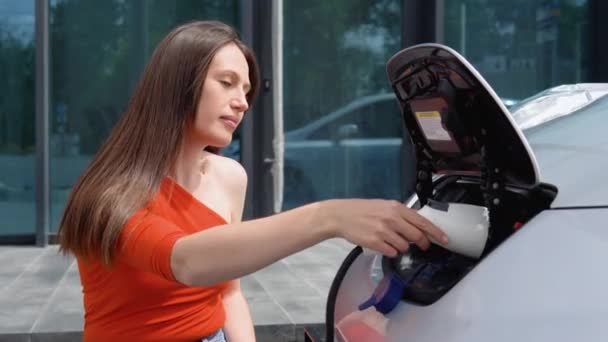 Mulher Coloca Carregador Seu Carro Elétrico Usar Telefone Quando Espera — Vídeo de Stock