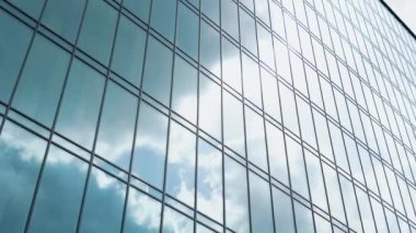 Bulutlar büyük bir ofis binasının camına yansıyor. Bulutları hareket ettirmek ofisin pencerelerine yansıyor.