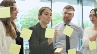 Genç şirket çalışanları ofiste çıkartmalarla bir iş planını tartışıyor.