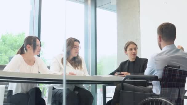 若い男性と女性のオフィスの従業員のグループは 会議や理事会室会議 車椅子で1つのプロジェクトに座って議論する — ストック動画