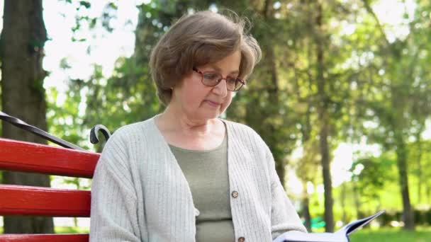 Ελκυστική Ηλικιωμένη Γυναίκα Απολαμβάνοντας Ανάγνωση Βιβλίων Στο Πάρκο Και Χαμογελώντας — Αρχείο Βίντεο
