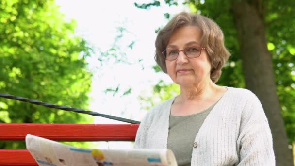 Ανώτερη Γυναίκα Διαβάζει Εφημερίδα Κάθεται Παγκάκι Στο Πάρκο Ηλικία Συνταξιοδότησης — Αρχείο Βίντεο