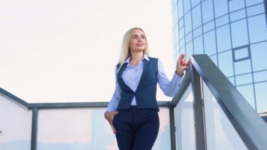 Modern bir şirket binasının önünde duran iyi giyimli, mutlu, üst düzey bir şirket yöneticisi.