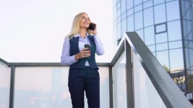 Dışarıdaki telefonu arayan mutlu iş kadınının portresi. Modern ofis binasının yakınında konuşan iş kadını