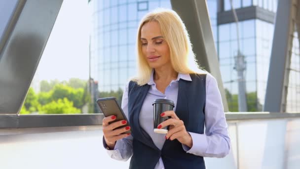 Kadını Kahve Fincanı Cep Telefonuyla Modern Bir Şirket Binasının Önünde — Stok video