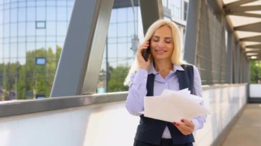 Dışarıdaki telefonu arayan mutlu iş kadınının portresi. Modern ofis binasının yakınında konuşan iş kadını