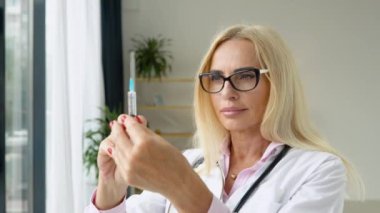 Kıdemli doktor elinde jeti salan bir şırınga tutuyor. Doktor kadın elinde şırınga tutuyor. Tıbbi şırınga hazır.
