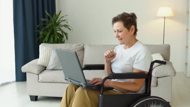 快乐的老年养恤金领取者网上冲浪信息 坐在轮椅上的成熟女人在家里的社交网络上聊天 — 图库视频影像