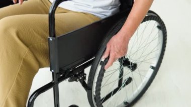 Kadın elinin evdeki tekerlekli sandalyeyi hareket ettirdiği yakın plan. Kadın ev işleriyle meşgul.