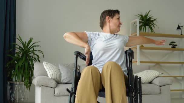 50多岁的女子正坐在轮椅的不同侧面张开双臂 — 图库视频影像