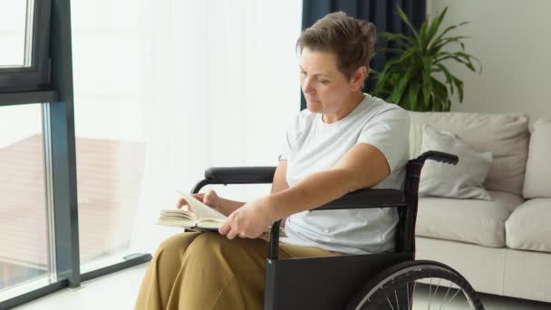 Seniorin Die Sitzt Rollstuhl Und Liest Hause Ein Buch — Stockvideo