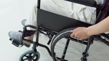 Kadın elinin evdeki tekerlekli sandalyeyi hareket ettirdiği yakın plan. Kadın ev işleriyle meşgul.