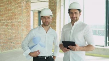 Two men in helmet look at the plan of the building
