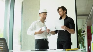 Two architect discussing help create plan with blueprint home building at office