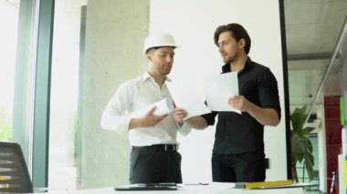 İki mimar ofis planlarıyla plan oluşturulmasına yardım ediyor.