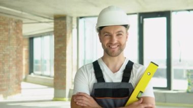 Kabarcık düzeyi cetvel yakın görünüm, ölçüm ve seviyelendirme kavramı. İnşaat alanında sarı denge cetvelli miğferli bir mühendisin portresi.