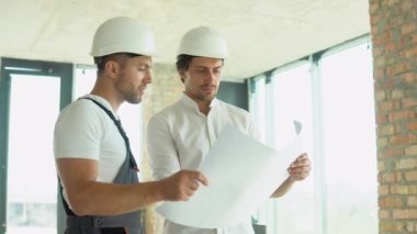 Two young engineer standing behind looking at a building site, wearing a safety helmet. Construction Business. Teamwork concept
