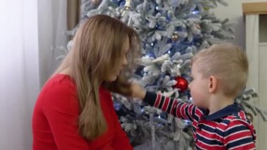 Küçük çocuk annesi Noel ağacı süslemek için yardım