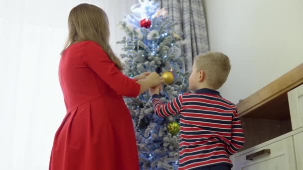 Mother Helping Little Boy Decorate Christmas Tree Home — Stock Video