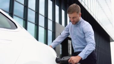 Sakallı adam elektrik tedarikçisini elektrikli arabaya bağlayamaz. Ekolojik modern elektrikli araçların işlem şarjı. Ulaşım için alternatif enerji