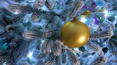 Traditional Christmas tree with gold ball ornament and glowing colorful lights in background