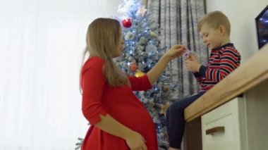 Küçük çocuk annesi Noel ağacı süslemek için yardım