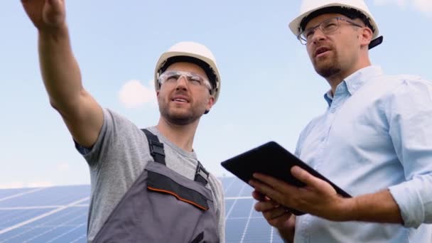两名身穿工作服和戴钢盔的年轻工人检查安装的太阳能电池板 绿色电力概念 — 图库视频影像
