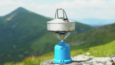Tencere dibin kara seninki benden kara, seninki benden kara. Tepenin zirvesinde dağın arka planına karşı yakın plan çekimde. Georgia 'daki Svaneti Ovası. Çay ya da kahve yapıyorum. Turist.