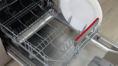 Male hands uploading dishwasher close up. House chores concept. Modern technologies for home.