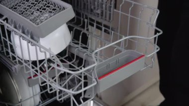 House chores concept.Housewife taking out clean plates from dishwasher machine. Female hands unloading dishwasher close up. Modern technologies for home.