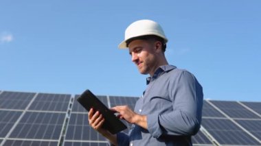Engineer solar photovoltaic panels station checks with tablet computer.
