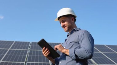 Engineer solar photovoltaic panels station checks with tablet computer.