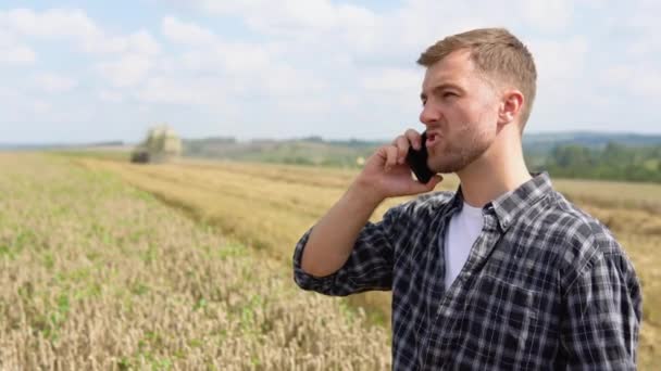 Farmer Using Cell Phone Holding Notebook Combine Harvester Wheat Field — Vídeo de Stock