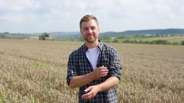 Happy Young Farmer Standing Wheat Field While Combine Harvester Background — Vídeo de stock