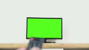 Watching chroma key TV and changing channel by remote control. Channel surfing internet TV green screen.