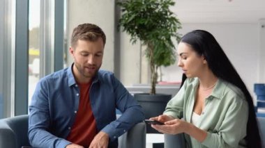 Concentrated male businessman looking at computer monitor, working with a young female worker on a project, people holding a video meeting with a client or interviewing a job candidate.
