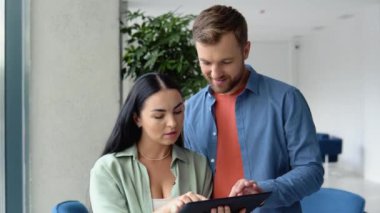 Smiling businesspeople work collaborate on computer, brainstorm over company startup at office meeting. Motivated diverse colleagues look at laptop screen discuss business project ideas together.