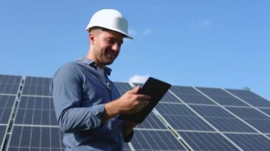 Engineer solar photovoltaic panels station checks with tablet computer.