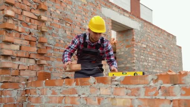 安装砖墙 穿着制服和安全设备的建筑工人在大楼里工作 — 图库视频影像