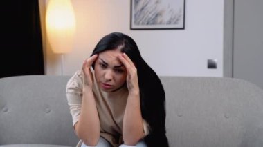 Stresli hissediyorum. Kanepede başı ağrıyan bir kadın.